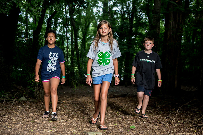 Three 4-H youth walking in the woods